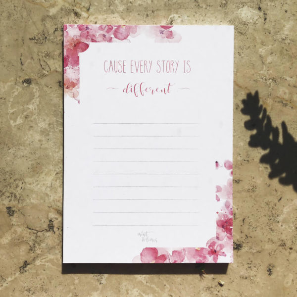 Notizblock mit pinkem Blumenmuster und Aufschrift "Cause every Story is different" auf Mamor.