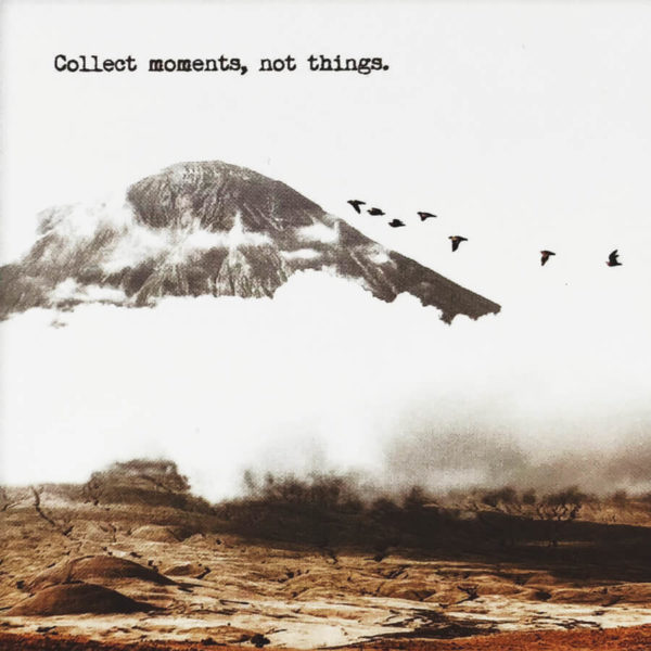 Nahaufnahme der Polaroid Karte mit Aufschrift "Collect moments, not things." und einem Berg mit Vögeln im Hintergrund.