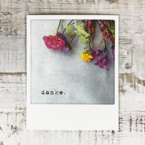 Polaroid Karte mit Aufschrift "Danke." und Blumen.