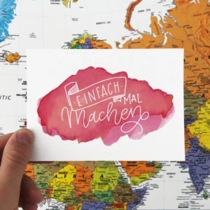 Postkarte mit Aufschrift "Einfach mal machen" vor einer Weltkarte fotografiert. Designt von Mint & Limes.