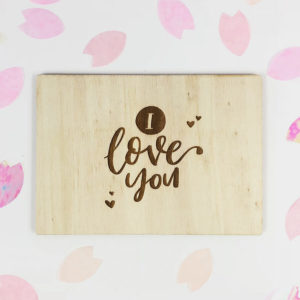 Holzpostkarte mit Aufschrift "I love you". Von oben fotografiert.