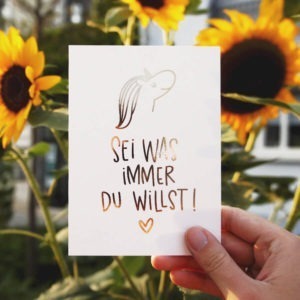 Postkarte mit Aufschrift "Sei was immer du willst!" mit Einhornkopf und Herz vor Sonnenblumen. Designt von Mint & Limes.
